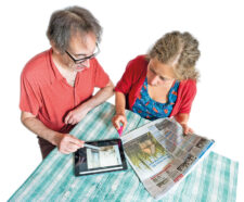 Paar bei der Wohnungssuche mit Tablet und Zeitung